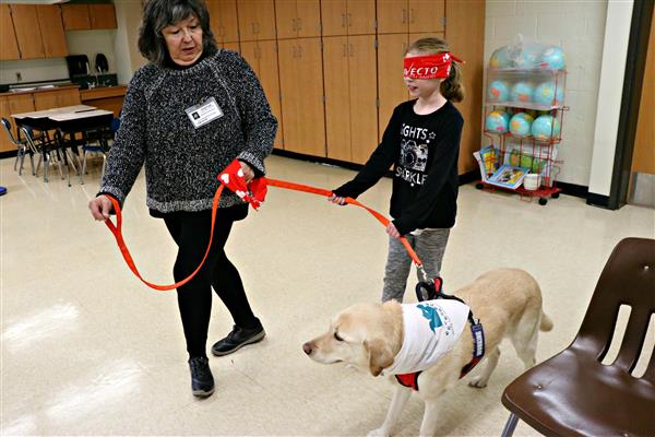 A student gets led around the classroom by Christi. 